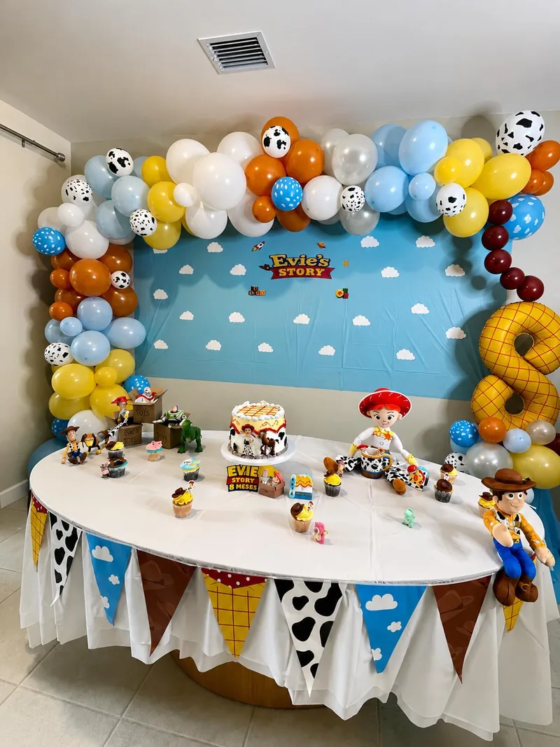 Blue, yellow, white and orange balloons with toy character props and a coordinated dessert table.
